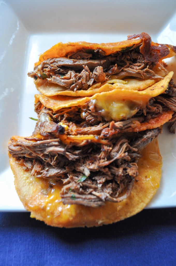 Two Birria de Res quesotacos on a plate. These tacos are from Little Miner Taco, which is a restaurantLittle Miner Taco is a restaurant with multiple locations in the Washington, D.C. Metro Area.
