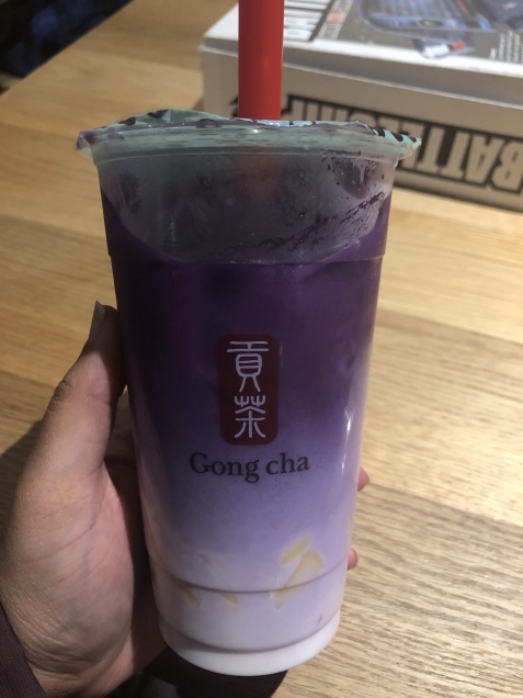 A hand holding a boba tea latte from Gong cha. The latte is called purple sweet potato latte.