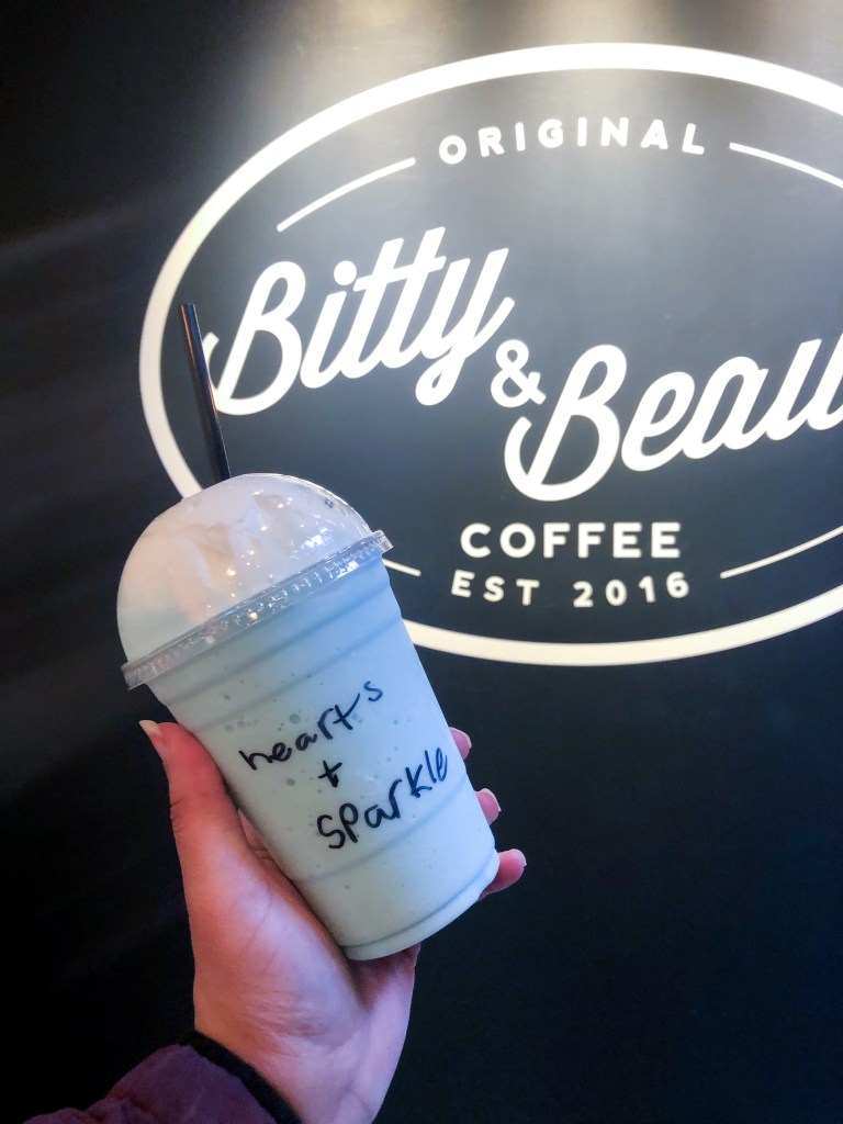 A cotton candy frappe in front of Bitty & Beau’s Coffee signage. Bitty & Beau's Coffee is a coffee shop in Annapolis, Maryland.