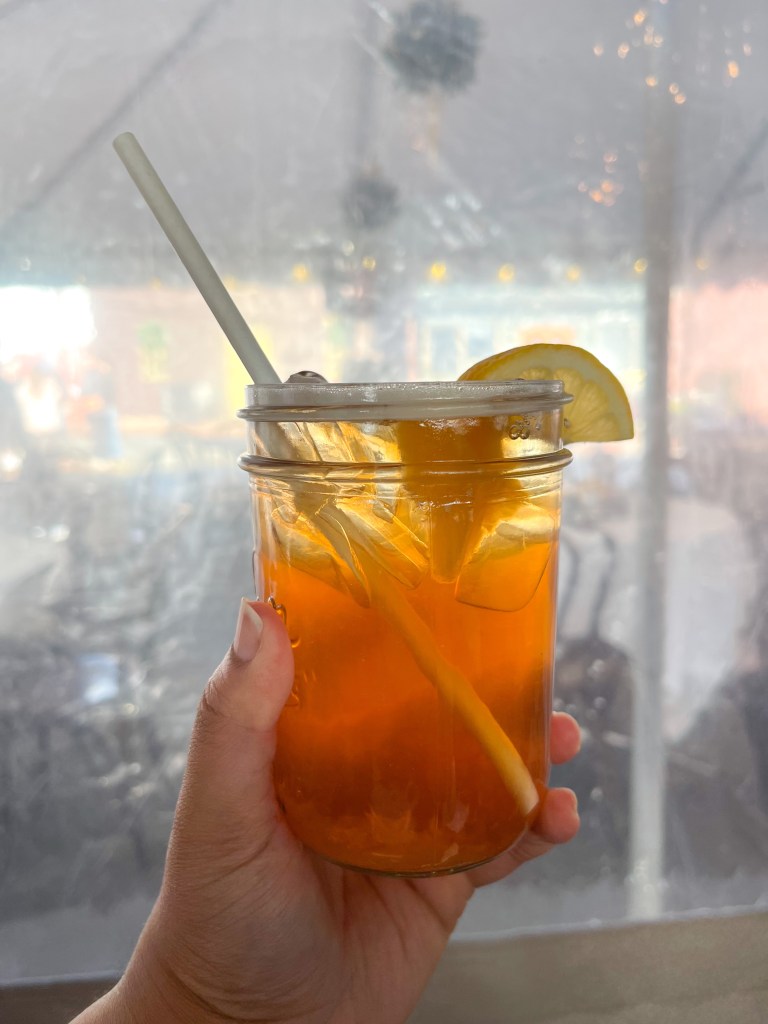 A hand holding a drink called "Southern Peach" at Iron Rooster, a restaurant located in Annapolis, Maryland.