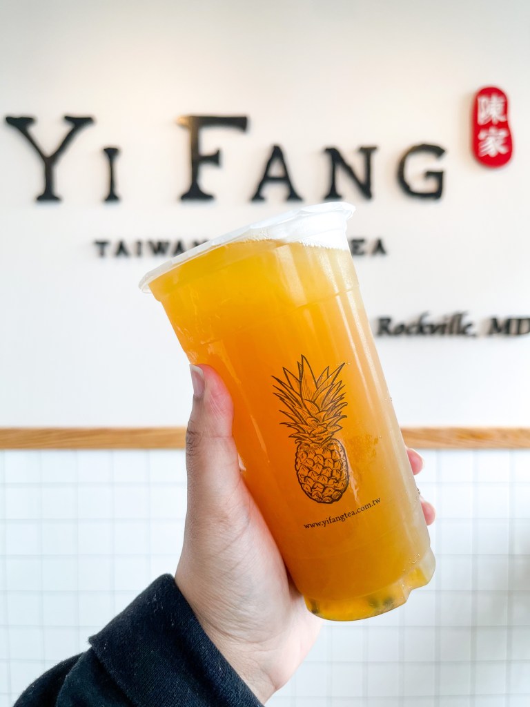 A hand holding a cup of Passionfruit Tea from YiFang, an bubble tea shop in Rockville, Maryland