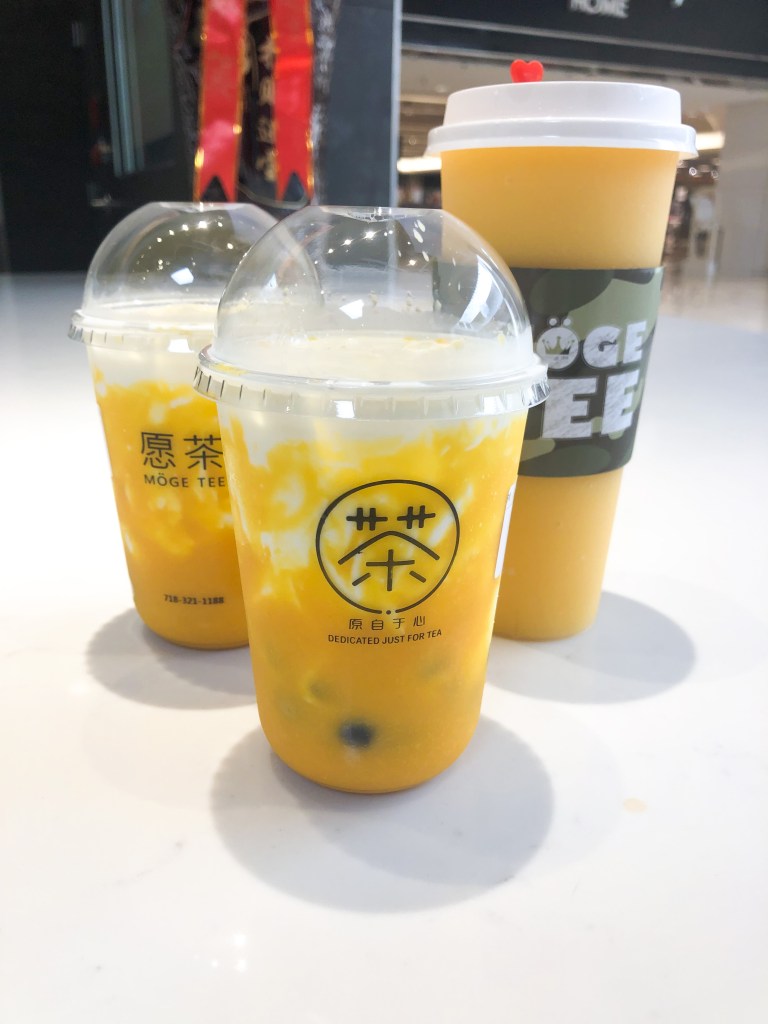 Three mango drinks sitting on the counter. These drinks are from Möge Tee, which is a bubble tea shop chain in the United States. These drinks were bought at their shop at Tysons Corner Mall in Virginia.