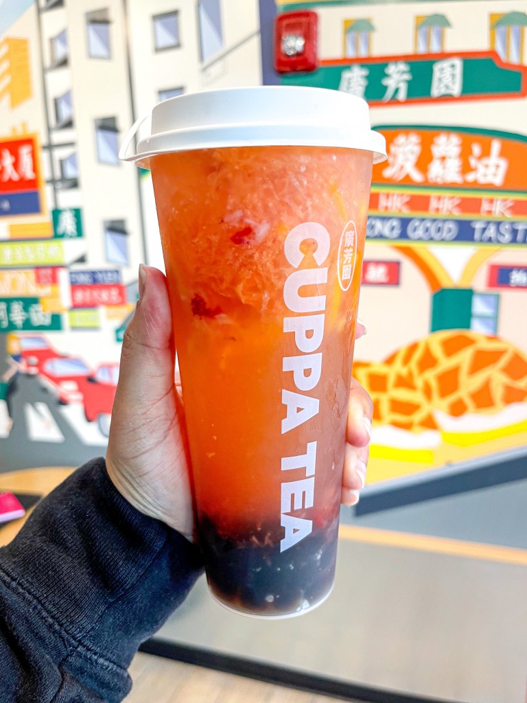 A hand holding a Super Fruit Iced Tea with boba pearls from Cuppa Tea, a shop in College Park, Maryland.