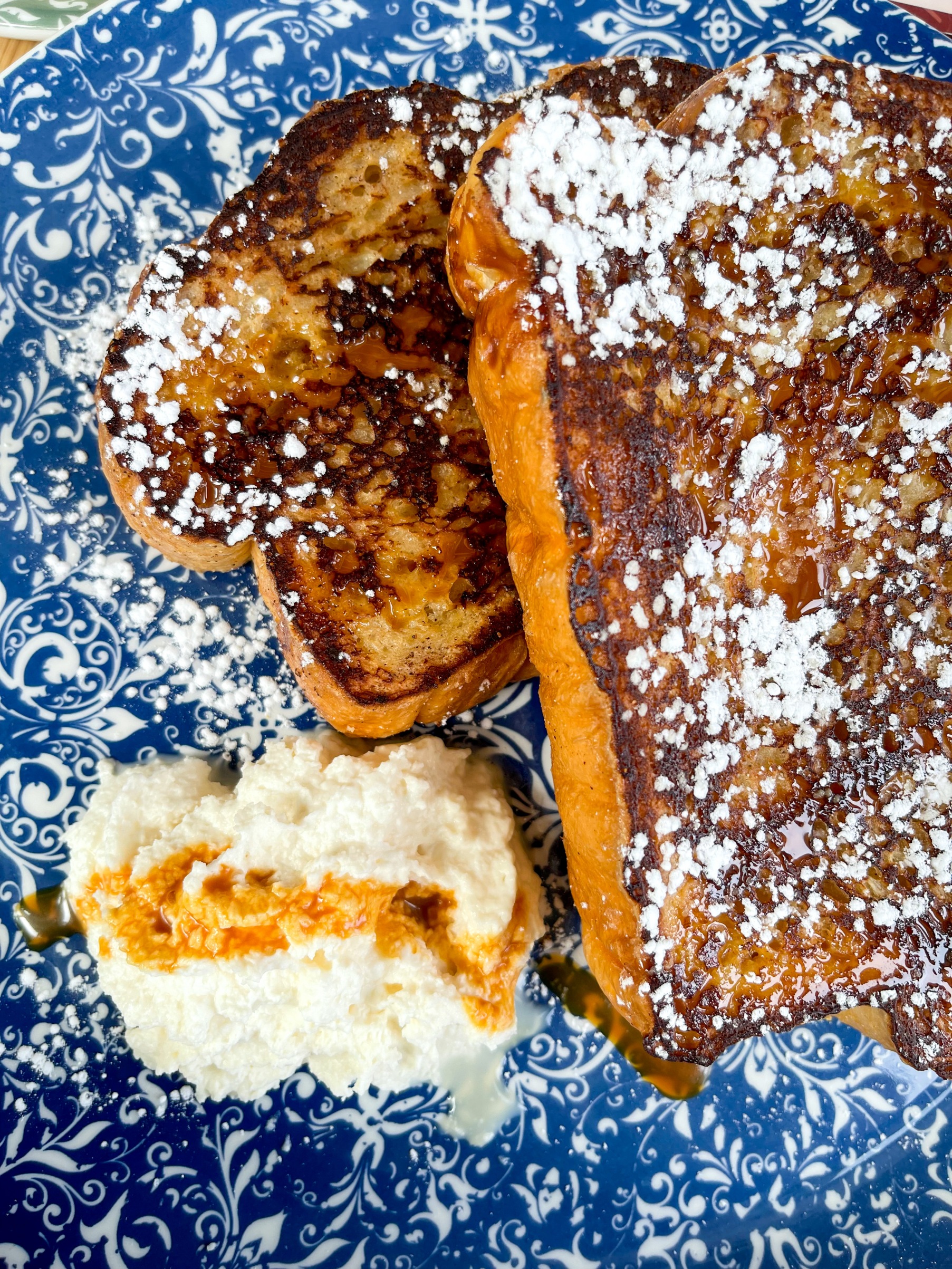 Two large slices of French toast with a side of Chantilly cream on a plate