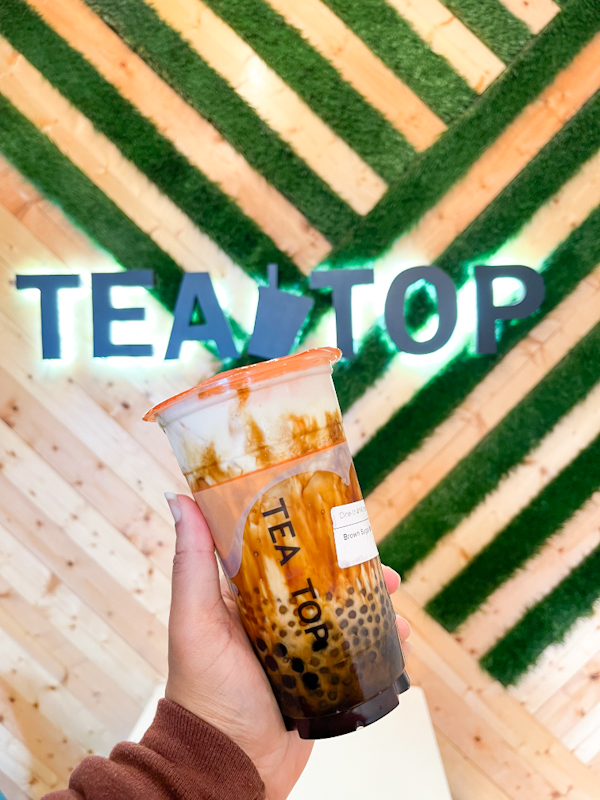 A hand holding a cup of brown sugar black tea from Tea Top, a boba tea shop in Ellicott City, Maryland