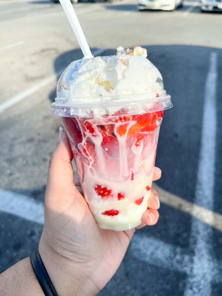A hand holding a strawberry dessert
