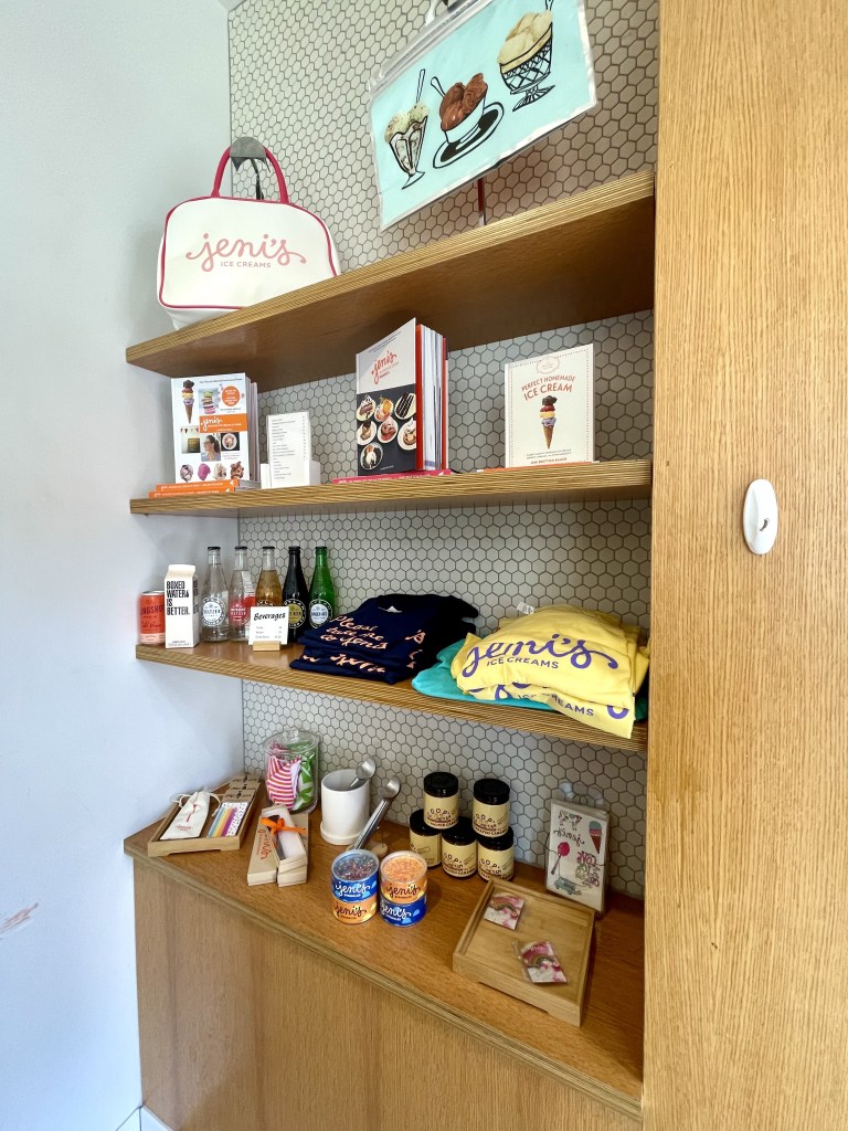 Merchandise at Jeni's Splendid Ice Creams, which includes t-shirts, a book, and a tote bag.