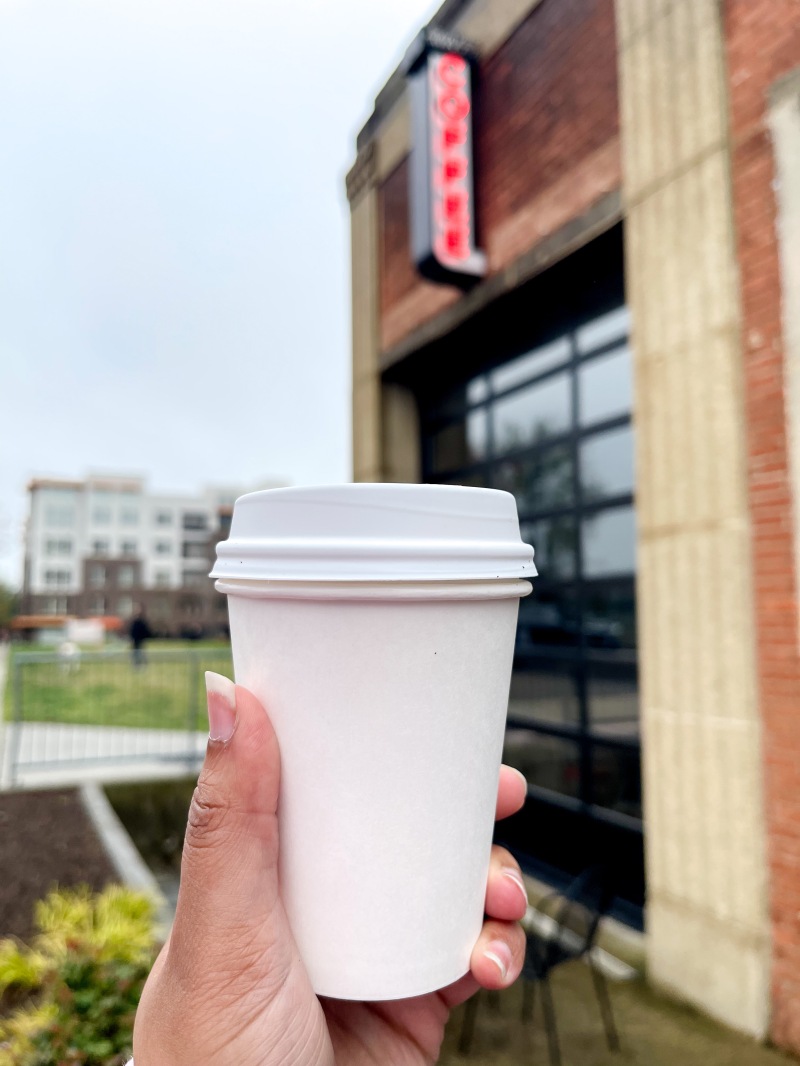 A hand holding a cappuccino from Swing's Coffee in Alexandria, Virginia