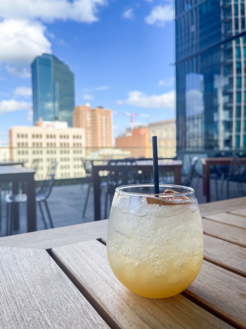 A cocktail sitting on a table with buildings in the background