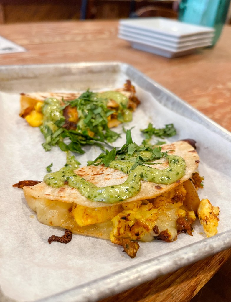 a tortilla with chorizo, eggs, cheese, and potatoes topped with a sauce and cilantro