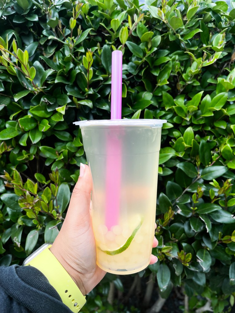 A hand holding a drink with boba pearls and a lime slice