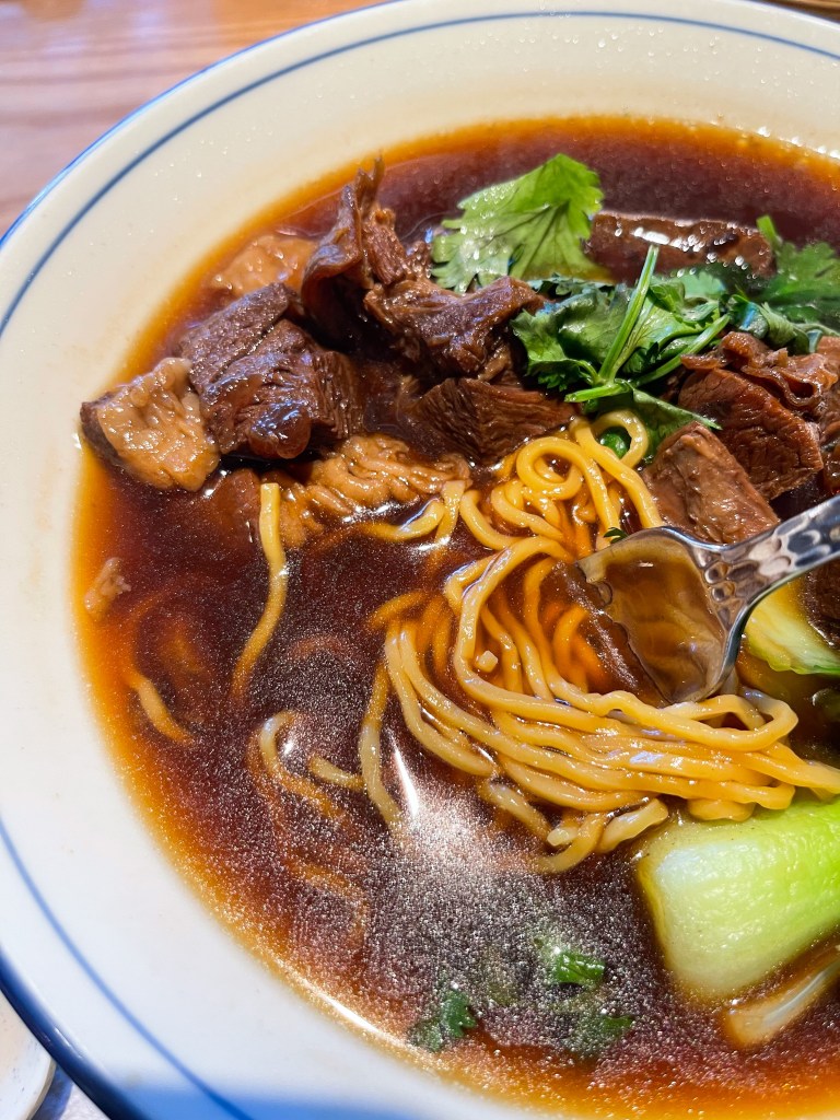 A soup with beef, noodles, and vegetalbes in a bowl