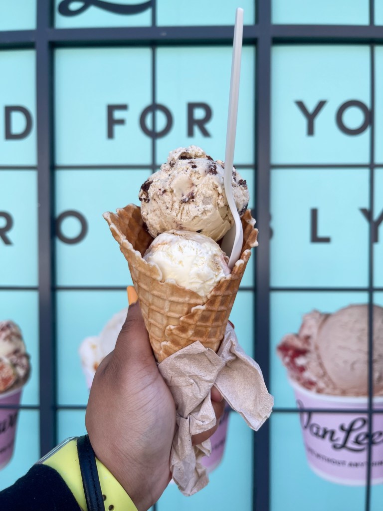 A hand holding an ice cream cone that has two scoops