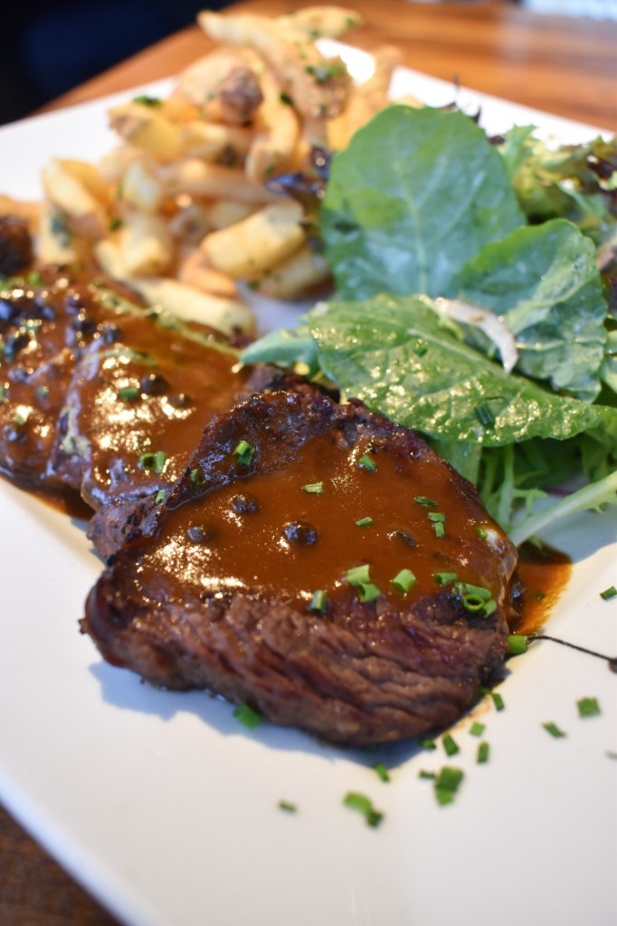 a plate with steak frites, fries, and salad