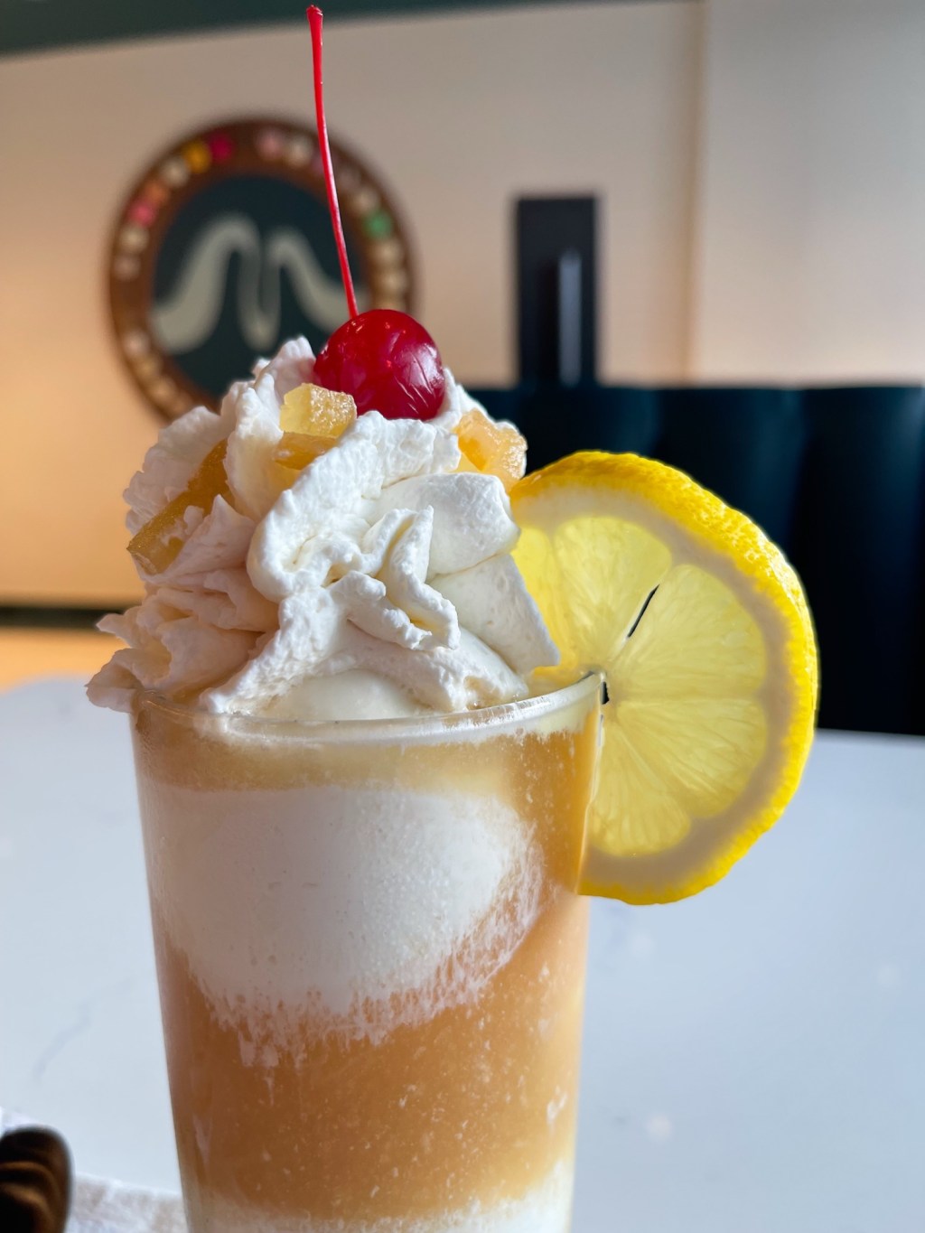 An ice cream float in a glass topped with whipped cream and a cherry sitting on a table