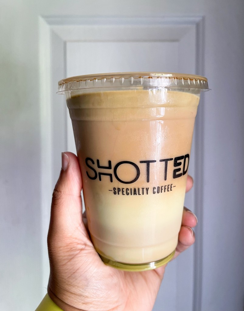 A hand holding an iced coffee